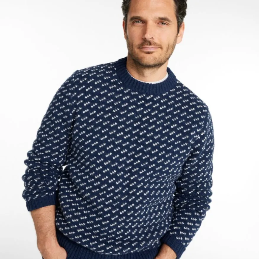 Man wearing a navy blue sweater with a white geometric pattern and ribbed cuffs and hem.